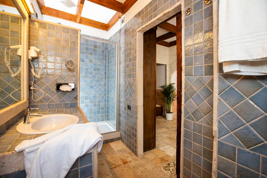 Bagno con mosaico blu e travi in legno