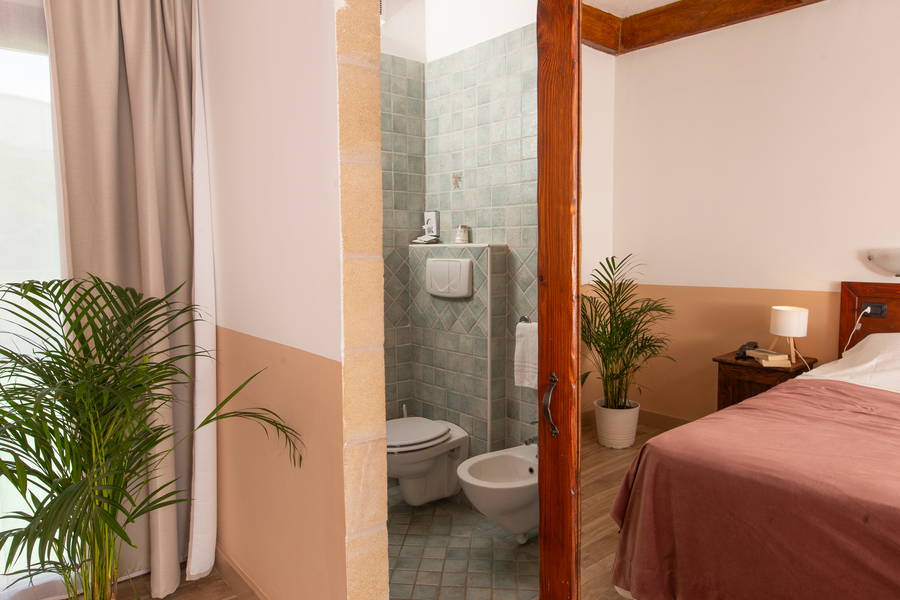 Bagno con piastrelle verde salvia e dettagli in legno
