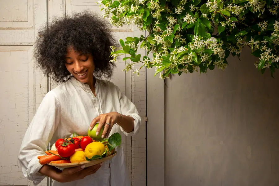 Ospite sorridente con un cesto di frutta e verdura di stagione accanto ai gelsomini