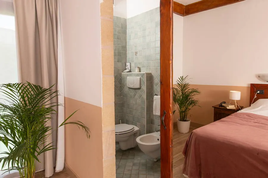 Bagno con piastrelle verde salvia e dettagli in legno